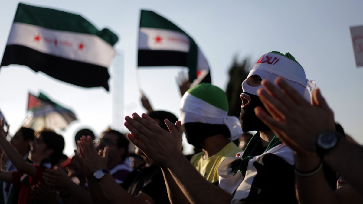 Masked Syrians with the revolutionary flag chant slogans against Bashar Assad, during a protest in front the Syrian embassy in Amman, Jordan, Thursday, June 28, 2012. (AP Photo/Mohammad Hannon)