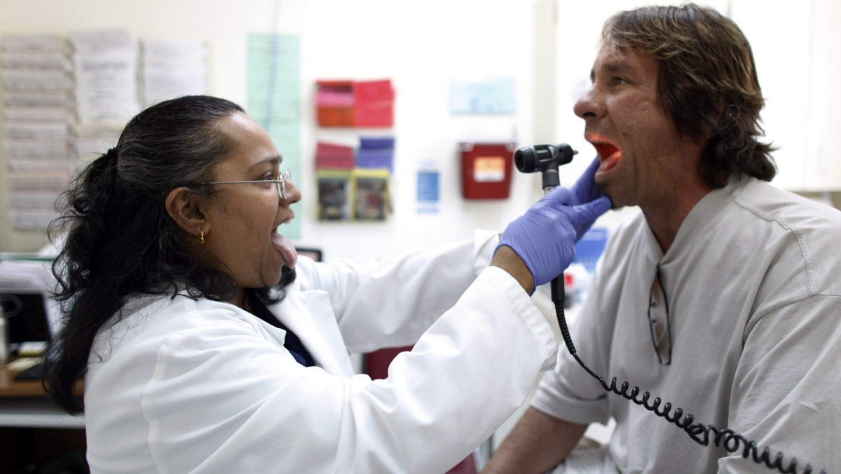 Dr. Hamsakumari Ramasubramaniam, left, examines patient Fabian Vasquez at Camillus Health Concern, Wednesday, June 27, 2012, in Miami. Camillus is a private, non-profit organization that provides health care to the homeless and poor in Miami-Dade County. (AP Photo/Lynne Sladky)