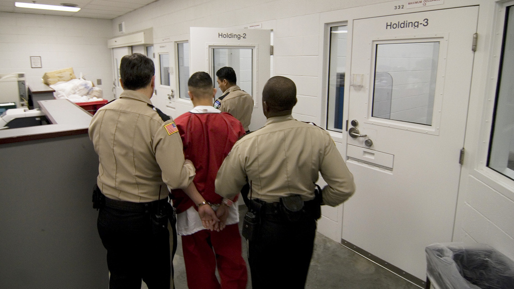 An inmate is walked down the hall of a detention center. (Photo by Common Language Project via Flikr)