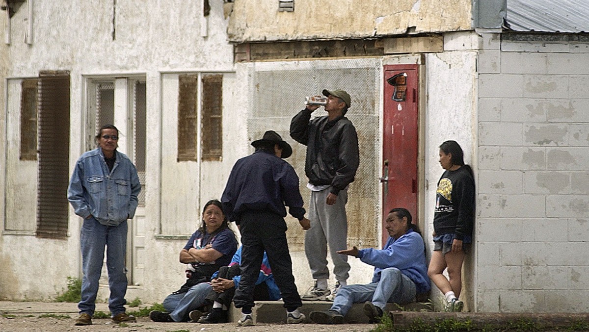 This June 7, 2003 file photo shows a man drinking a beer standing with other Native Americans on the streets of Whiteclay, Neb.The Oglala Sioux Tribe announced Thursday, Feb. 6, 2012, that it will file a $500 million federal lawsuit against some of the nation's largest beer distributors, alleging that they knowingly contributed to the chronic alcoholism, health problems and other social ills on the Pine Ridge Indian Reservation. The lawsuit also targets the four beer stores in Whiteclay, a Nebraska town (pop. 11) on the South Dakota border that sells about 5 million cans of beer per year. (AP Photo/William Lauer, File)