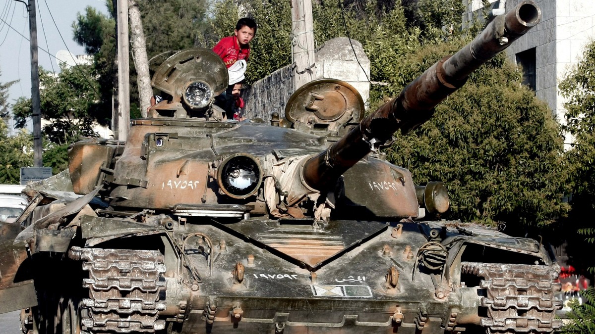 In this Tuesday, July 24, 2012 photo, a Syrian boy sits atop a damaged military tank at the border town of Azaz, some 20 miles (32 kilometers) north of Aleppo, Syria. (AP Photo/Turkpix)