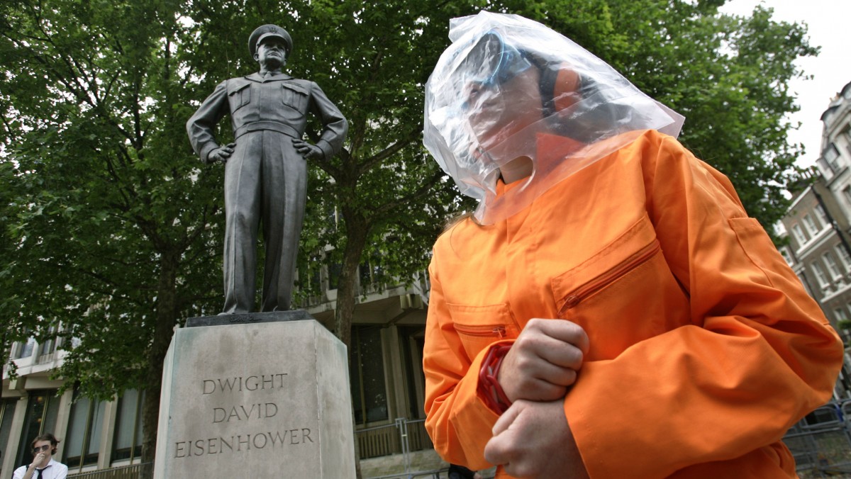 Under the statue of former U.S. President Dwight D. Eisenhower outside the U.S embassy in central London, a protester dressed as 'Guantanamo Bay prison detainee' in orange jumpsuit and a plastic bag on her head as a hood, participates in a play called 'Closing Down Torture Airlines' during a demonstration.
