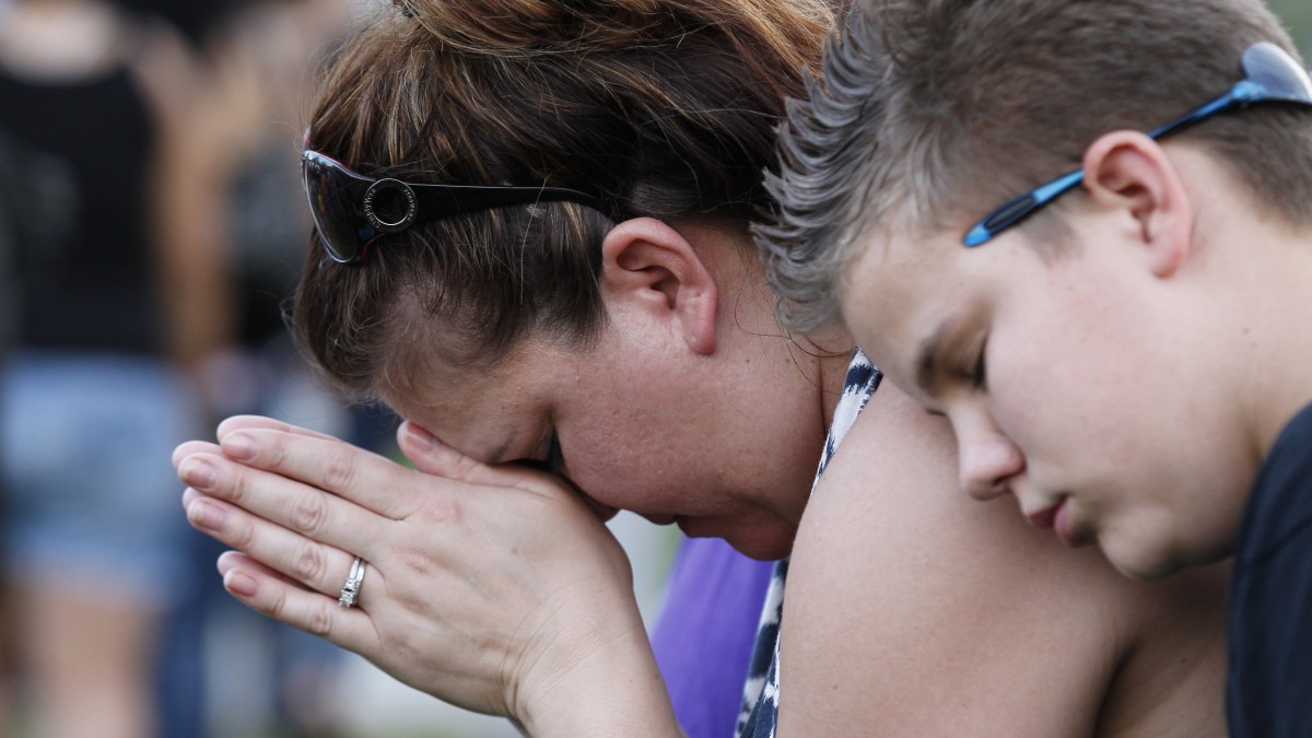 Dylan Bowen, 13, right, holds onto his mother Lorri Hastings, as they pray, Sunday, July 22, 2012 in Aurora, Colo., during a prayer vigil for the victims of Friday's mass shooting at a movie theater. (AP Photo/Alex Brandon)