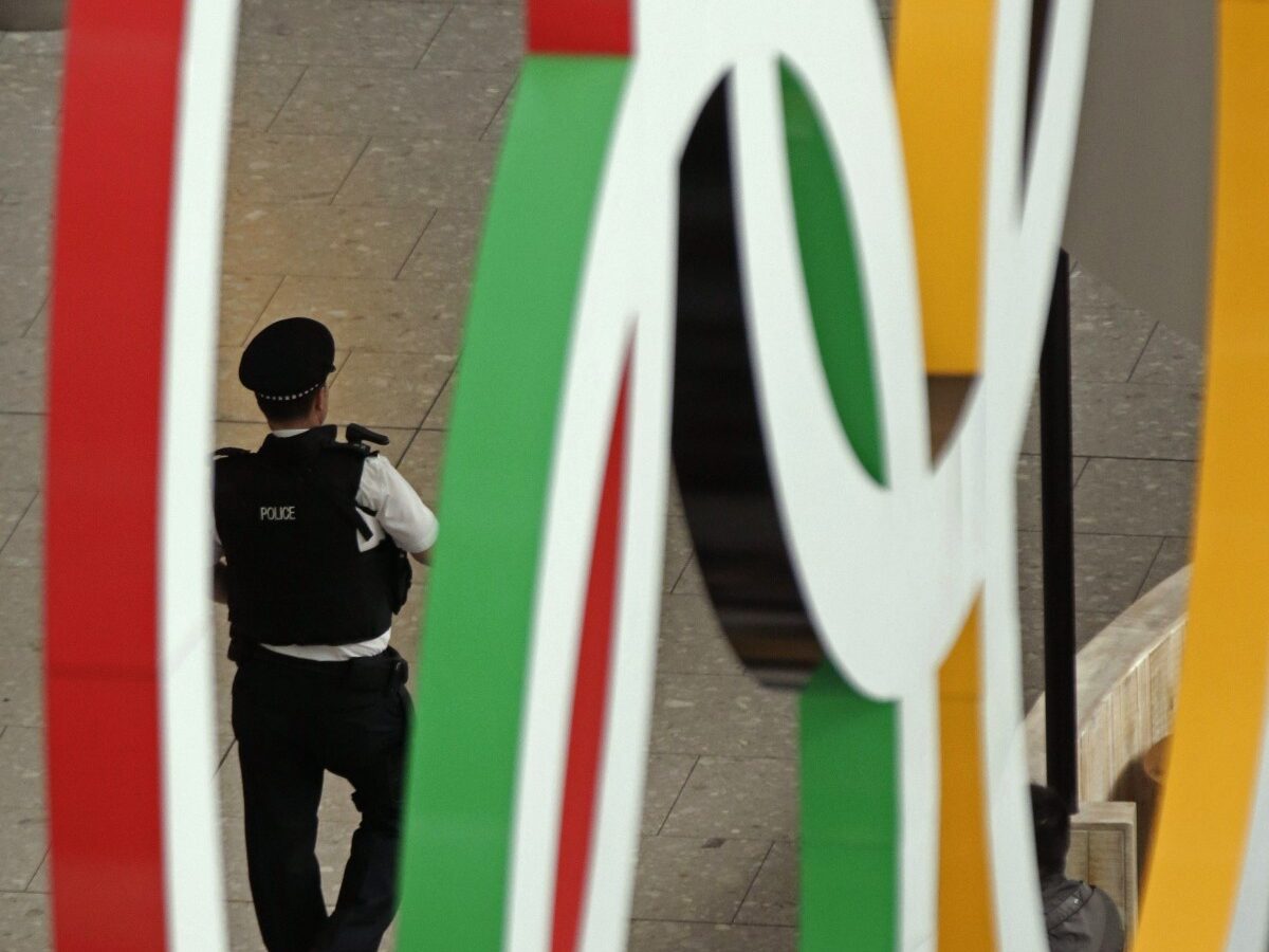 An airport police officer is framed by the Olympic Rings as he patrols an arrival terminal at Heathrow Airport, Tuesday, July 17, 2012 as London prepares for the 2012 Summer Olympics. (AP Photo/Charlie Riedel)