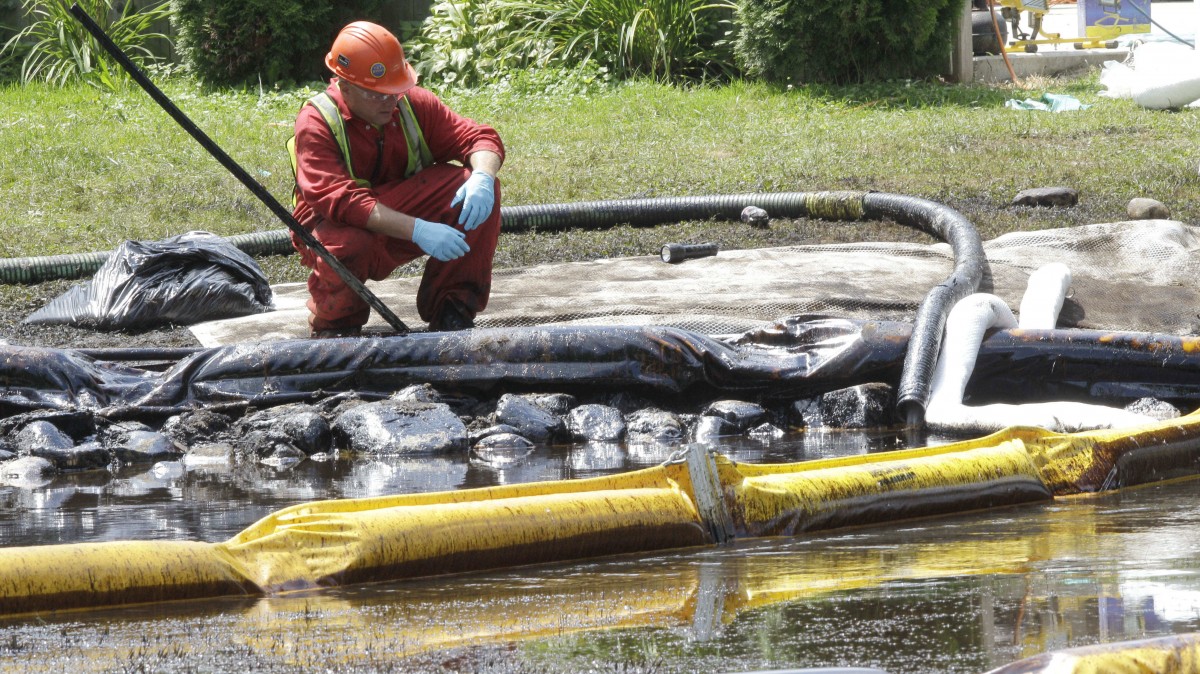 In this July 29, 2010, file photo, a worker monitors water in Talmadge Creek in Marshall Township, Mich., near the Kalamazoo River as oil from a ruptured pipeline, owned by Enbridge Inc. (AP Photo/Paul Sancya, File)