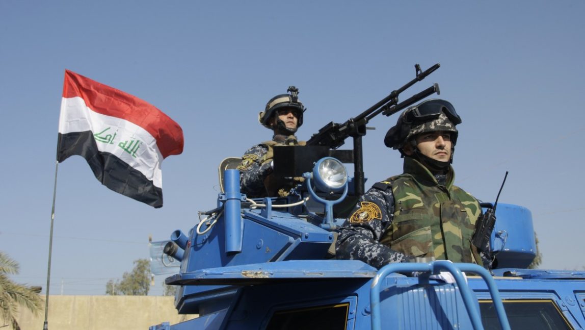 In this Nov. 22, 2011 file photo, the Iraqi flag waves while federal police parade in Baghdad. A report by the U.S. Special Inspector General for Iraq Reconstruction, to be released Monday, July 30, 2012, found that the American Embassy in Baghdad never got a written commitment for Iraq to participate in what initially was envisioned as a five-year, multibillion-dollar effort to train security forces after the U.S. military left last December. (AP Photo/Khalid Mohammed, File)