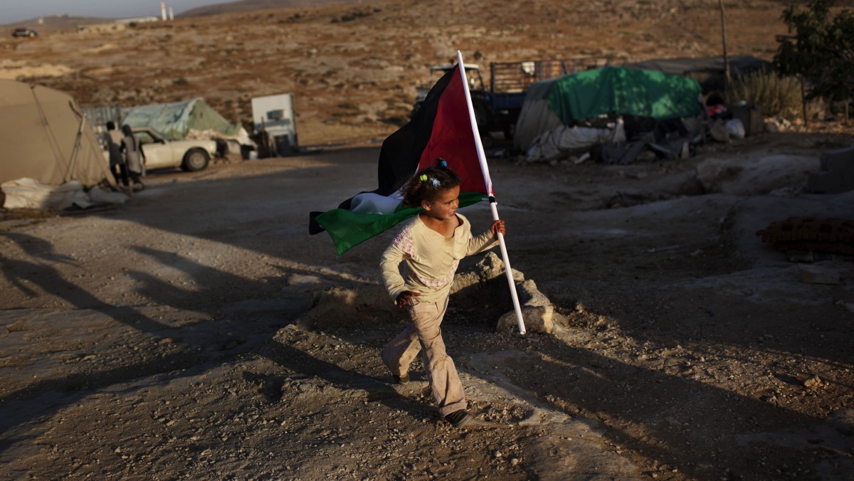 In this Friday, June 15, 2012 photo, a Palestinian girls carries a Palestinian flag in the West Bank town of Susiya. (AP Photo/Bernat Armangue)