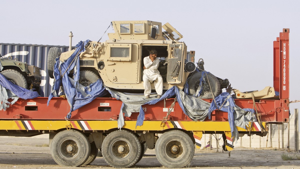 In this Friday, July 6, 2012 photo, Pakistani driver, Ihsanullah, 45, speaks on his mobile phone on top of a truck carrying NATO Humvees at a terminal in the Pakistani-Afghan border, in Chaman, Pakistan. (AP Photo/Matiullah Achakzai)