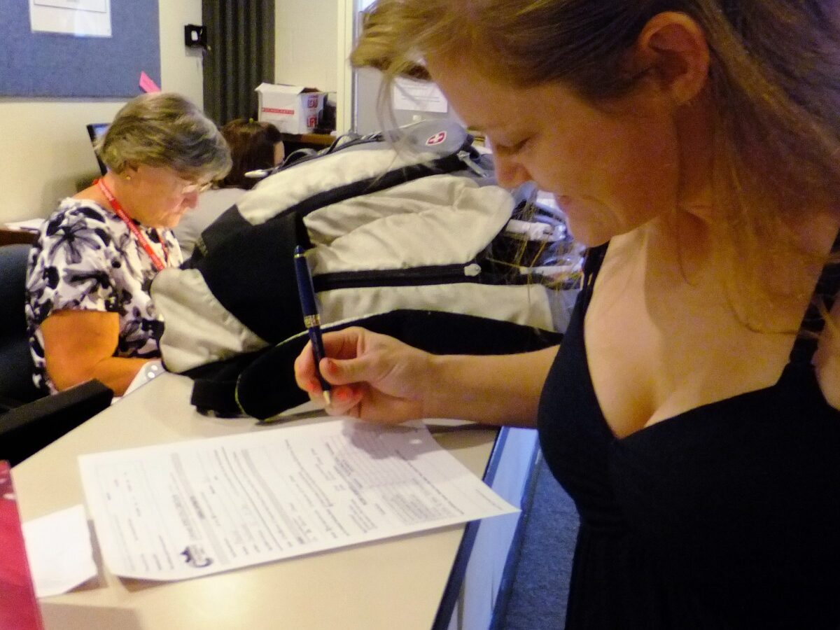 In this July 16, 2012, photo, Laura Fritz, 27, left, with her daughter Adalade Goudeseune fills out a form at the Jefferson Action Center, an assistance center in the Denver suburb of Lakewood. (AP Photo/Kristen Wyatt)