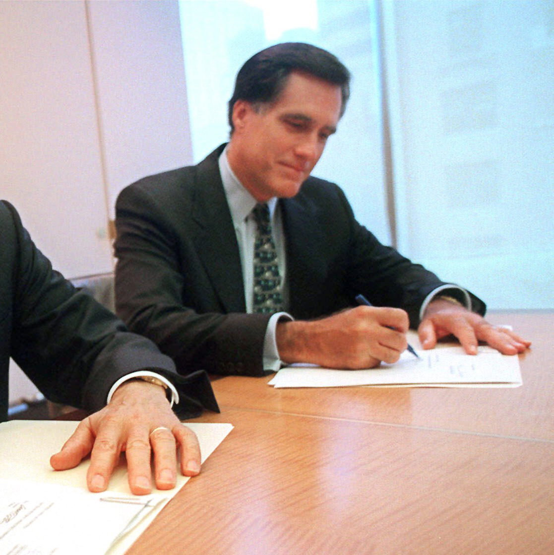 In this Sept. 25, 1998 file photo, provided by Domino's Pizza, Thomas Monaghan, founder and chairman of Domino's Pizza, Inc., left, and Mitt Romney, managing director of Bain Capital, Inc., sign an agreement for Monaghan to sell a "significant portion" of his stake in the company to Bain Capital, in New York. (AP Photo/Domino's Pizza, Scott Gries, File)
