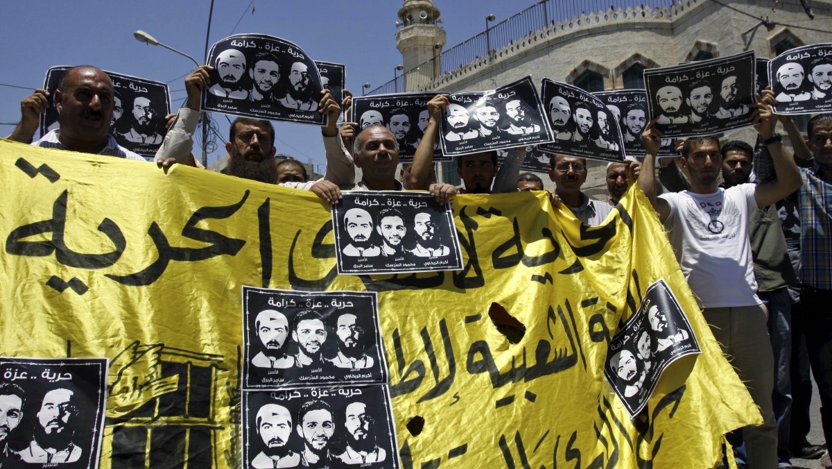 Palestinians hold posters showing Mahmoud Sarsak, center, a former player with the Palestinian national football team, Akram Rikhawi, right, and Samer Al-Barq, left, during a demonstration in support of Palestinians prisoners held in Israeli jails, in the West Bank town of Jenin, Saturday, June 9, 2012. (AP Photo/Mohammed Ballas)