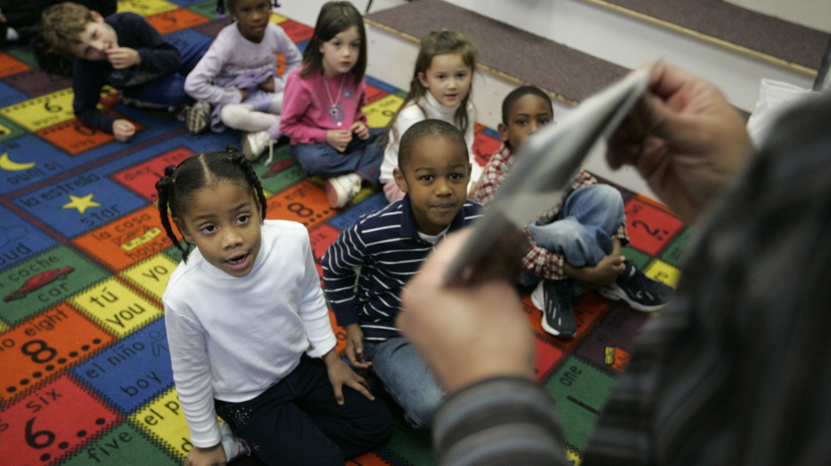 A teacher uses flash cards to teach kindergarten students including Nailiah Harping, 6, seated at left of the front row, and Jason Moncure, also 6, next to her her during Spanish class at the charter school Oakhurst Elementary in Decatur, Ga. (AP Photo/John Amis)