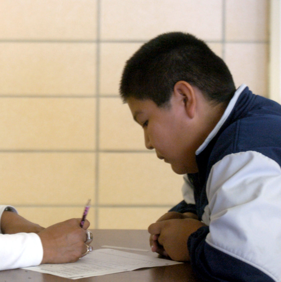 Michele Hernandez, left, a tutor at IT Stoddard Elementary School in Blackfoot, Idaho, takes a moment out of her lunch duties to assist Austin Tracy, 11, with his math homework. (AP Photo/Joshua Duplechian)