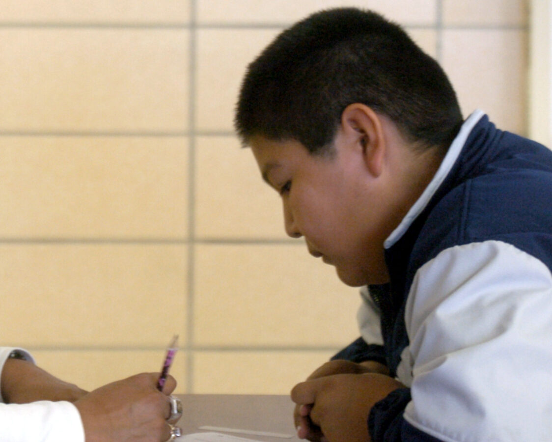 Michele Hernandez, left, a tutor at IT Stoddard Elementary School in Blackfoot, Idaho, takes a moment out of her lunch duties to assist Austin Tracy, 11, with his math homework. (AP Photo/Joshua Duplechian)