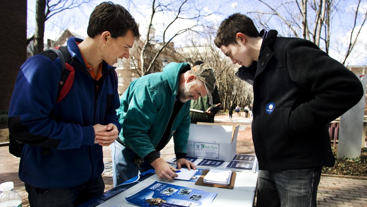 Young Obama student volunteers Mike Stratta, left, and Christo Logan, right, assist University of Pennsylvania worker Dave Munson, 45, fills up a voter registration form on University of Pennsylvania campus, in Philadelphia, Thursday, March 20, 2008. (AP Photo/Manuel Balce Ceneta)