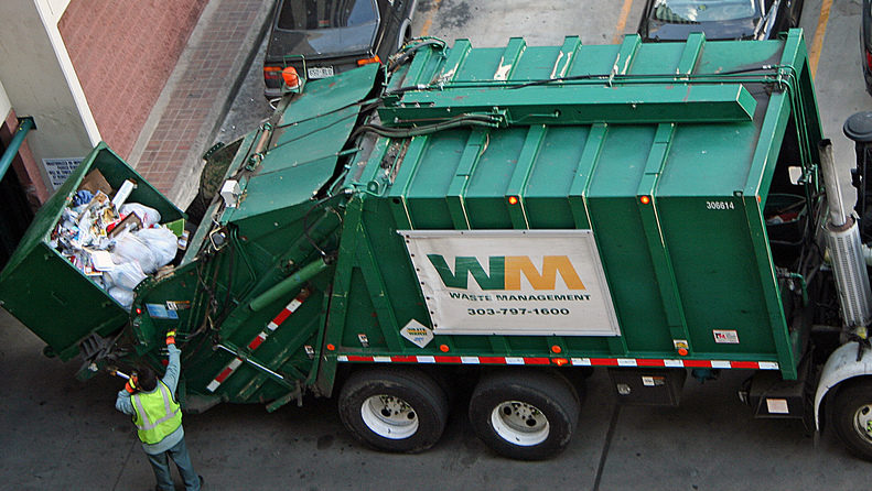 A Waste Management worker empties a garbage container into a company truck. (Photo by Jeffrey Beall via Flikr)