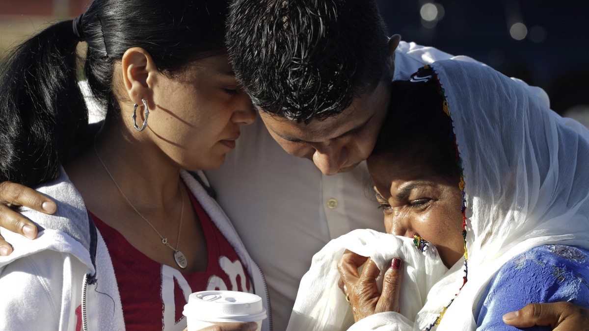 Amardeep Kaleka, son of the president of the Sikh Temple of Wisconsin, center, comforts members of the temple, Monday, Aug. 6, 2012, in Oak Creek, Wis., where a gunman killed six people a day earlier, before being shot and killed himself by police. (AP Photo/M. Spencer Green)