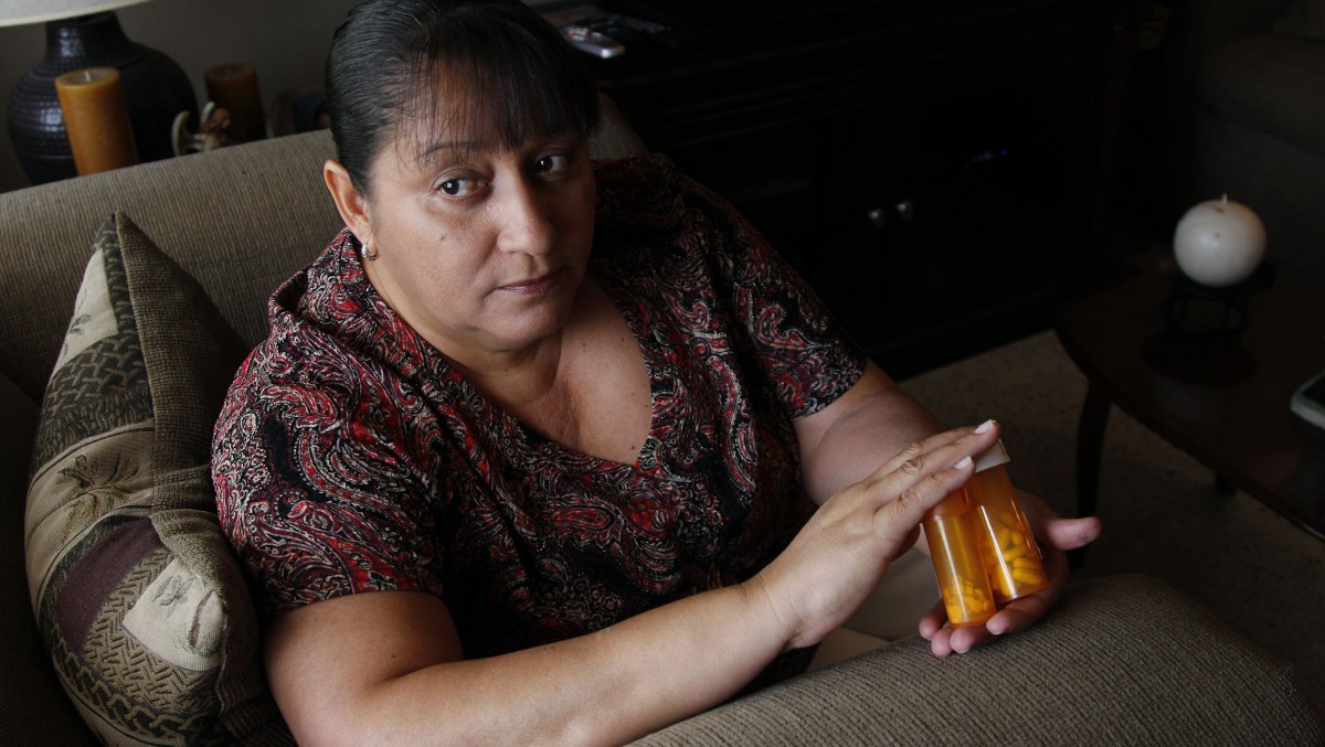 In a Thursday, July 26, 2012 photo, Sandra Pico, 52, holds medications she takes, at her home in North Miami Beach, Fla. Pico makes about $15,000 a year working about 20 hours a week as a home health aide, a bit too much to qualify for Medicaid, but not enough that she can afford private insurance. (AP Photo/Lynne Sladky)