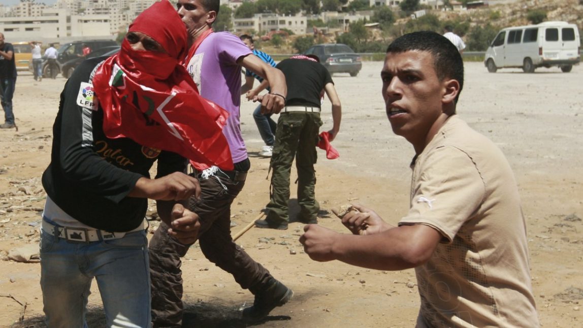 Palestinians hurl stones at Israeli troops, not seen, during a Democratic Front for the Liberation of Palestine (DFLP) demonstration supporting prisoners in Israeli jails outside the Ofer military prison, near the West Bank city of Ramallah, Thursday, Aug. 9, 2012. (AP Photo/Majdi Mohammed)