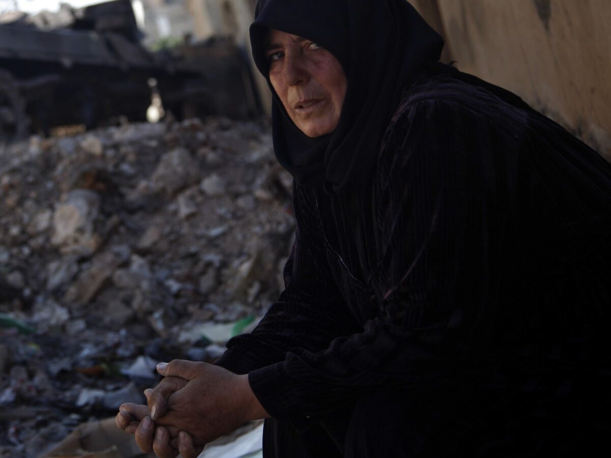 In this Sunday Aug. 5, 2012 photo, a Syrian woman looks on as she sits next to a destroyed military vehicle in the town of Atareb on the outskirts of Aleppo, Syria. (AP Photo)