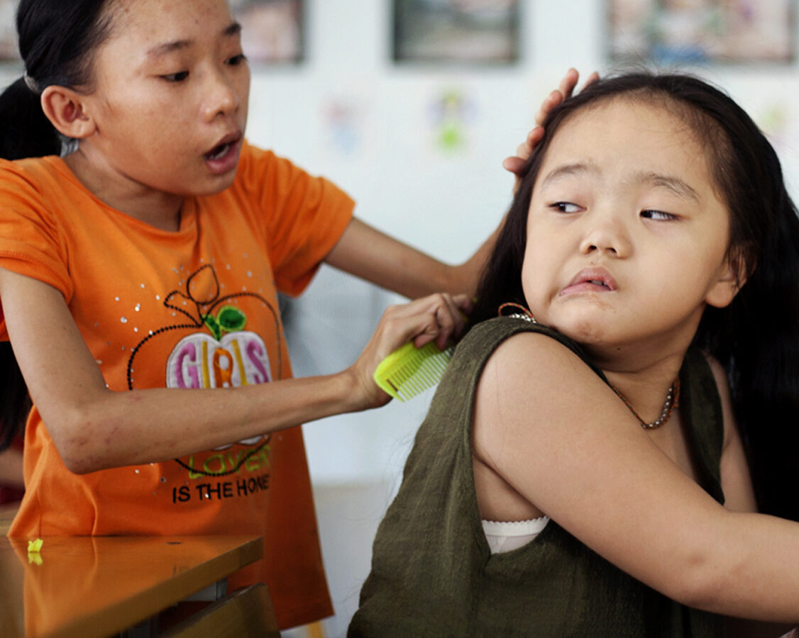 Ho Thi Lang, in the left, was combing Ngo Diep Uyen's hair after her nap at a rehabilitation center in Danang, Vietnam Tuesday Aug. 7, 2012. (AP Photo/Maika Elan)