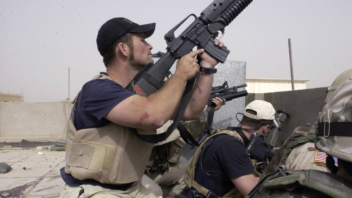 In this April 4, 2004 file photo, plainclothes contractors working for Blackwater USA take part in a firefight as Iraqi demonstrators loyal to Muqtada al-Sadr attempt to advance on a facility being defended by U.S. and Spanish soldiers in the Iraqi city of Najaf. (AP Photo/Gervasio Sanchez, File)