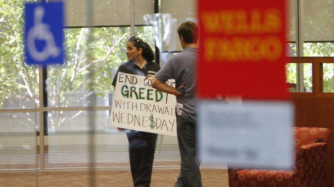 An Occupy San Diego protestor holds a sign urging bank withdrawals while waiting to close her account in a Wells Fargo bank branch Wednesday, Nov. 2, 2011 in downtown San Diego. (AP Photo/Lenny Ignelzi)