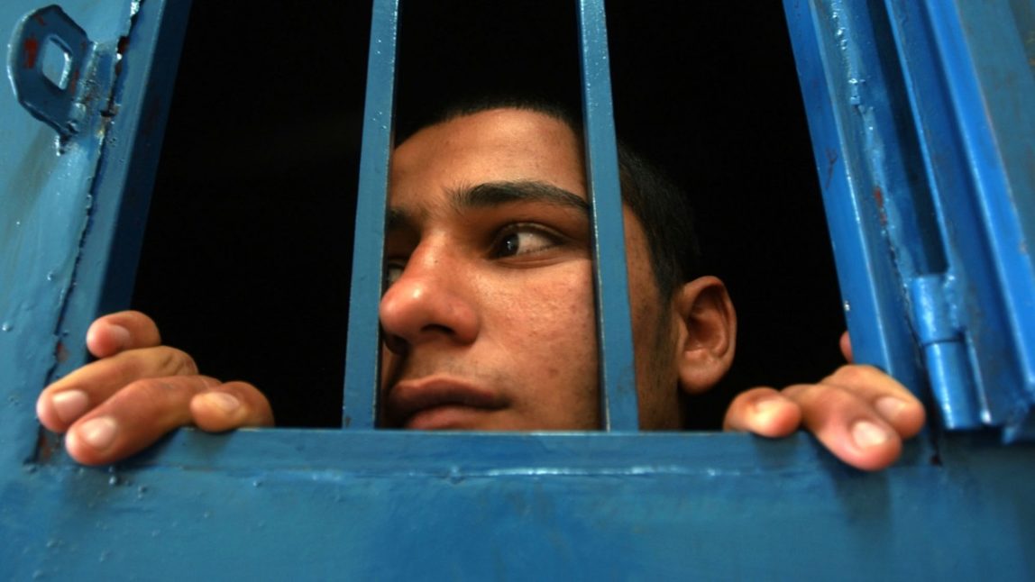 A boy prisoner looks on from his one-man cell at a juvenile prison Sunday, March 28, 2004. (AP Photo/Muhammed Muheisen)