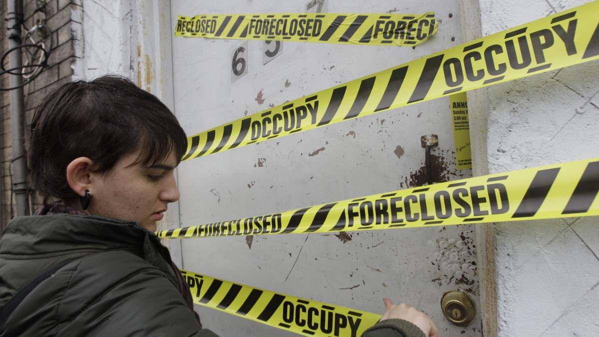 A Occupy Wall Street activist places tape on a boarded up house during a tour of foreclosed homes in the East New York neighborhood of the Brooklyn borough of New York, Tuesday, Dec. 6, 2011. (AP Photo/Mary Altaffer)