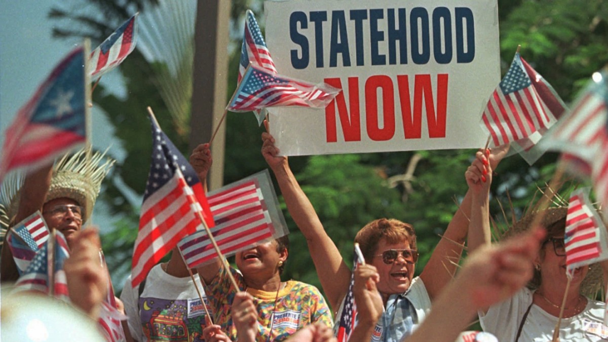 Supporters of Puerto Rico's pro-statehood movement cheer the arrival of Governor Pedro Rossello outside status hearings being held in San Juan, Puerto Rico Saturday. (AP Photo/John McConnico)