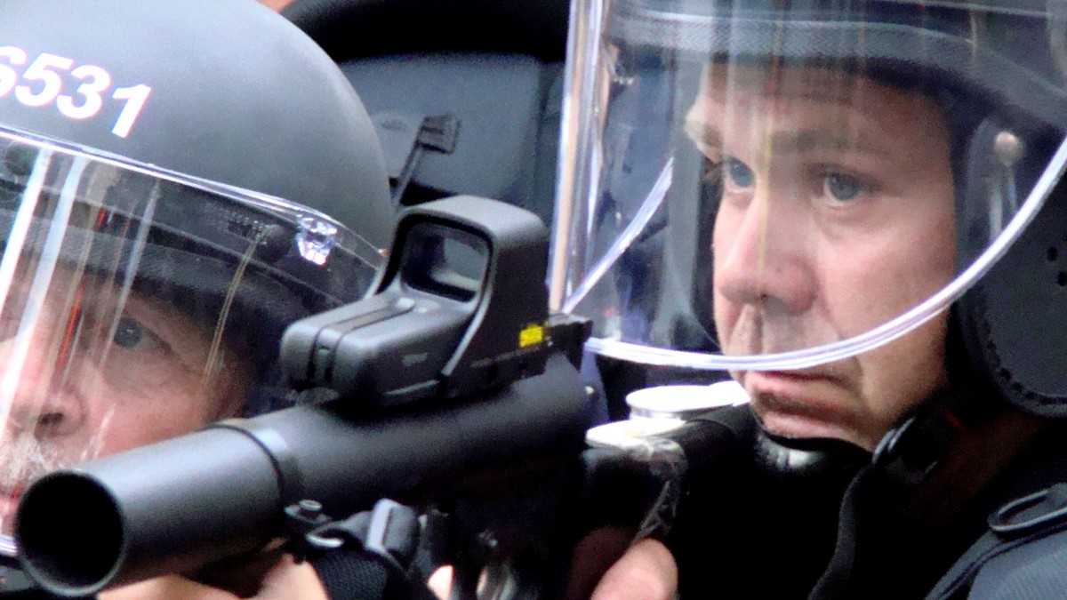 A police officer raises his weapon during a protest at the Republican National Convention in St. Paul, Minn., Tuesday, Sept. 2, 2008. (AP Photo/Kathryn Grim)