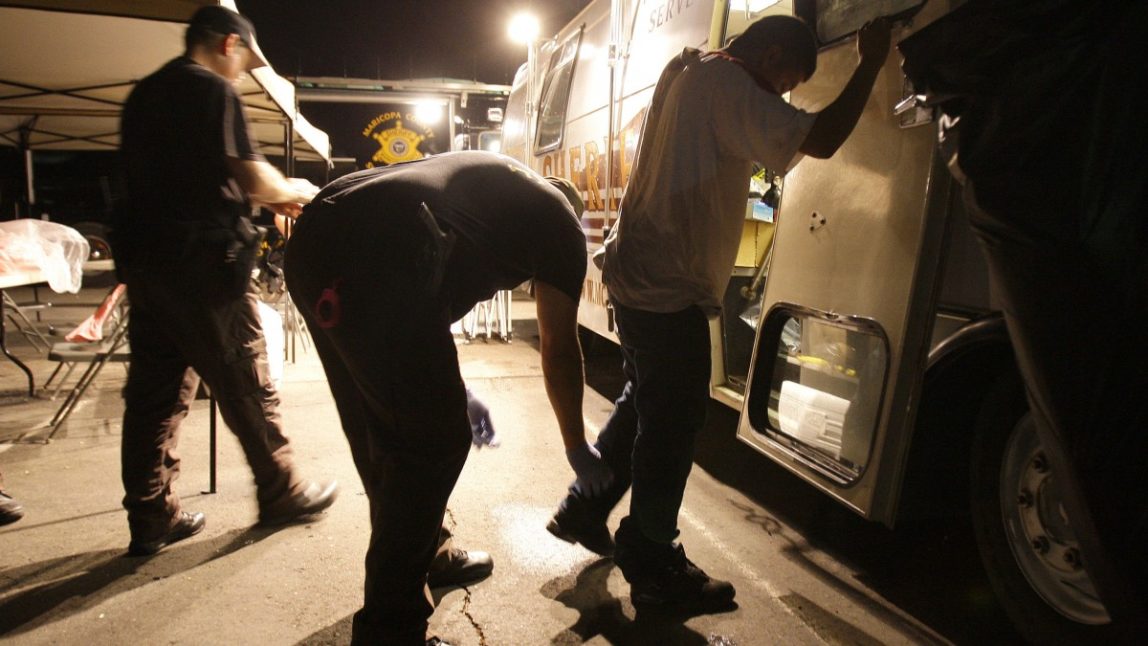 In this July 29, 2010 file photo, Maricopa County Sheriff's deputies, left, check the shoes of a suspect arrested during a crime suppression sweep in Phoenix. (AP Photo/Ross D. Franklin, File)