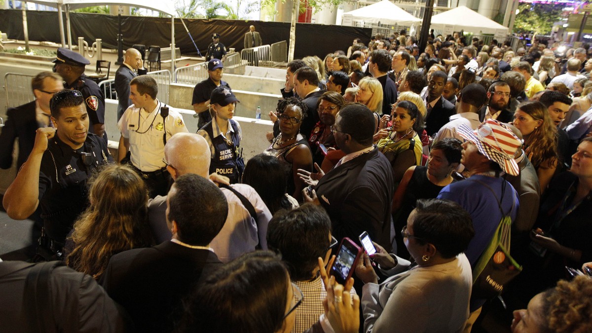 A security official speaks to convention goers as they were asked to move outside a security zone, Wednesday, Sept. 5, 2012, in Charlotte, N.C., during the second day of the Democratic National Convention.The entrance was delayed because of safety concerns. (AP Photo/Chuck Burton)