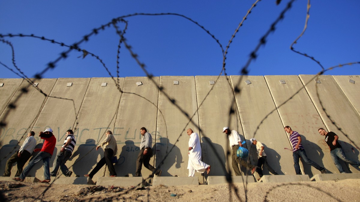 Palestinian men walk towards an Israeli checkpoint on their way to pray at the Al-Aqsa Mosque in Jerusalem, on the last Friday of the Muslim holy month of Ramadan near the West Bank city of Ramallah, Friday, Aug. 17, 2012. (AP Photo/Majdi Mohammed)