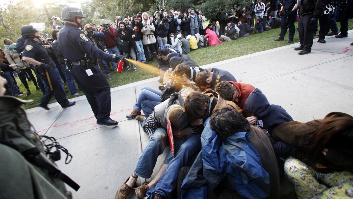 In this Nov. 18, 2011 file photo, University of California, Davis Police Lt. John Pike uses pepper spray to move Occupy UC Davis protesters while blocking their exit from the school's quad in Davis, Calif. (AP Photo/The Enterprise, Wayne Tilcock, File)