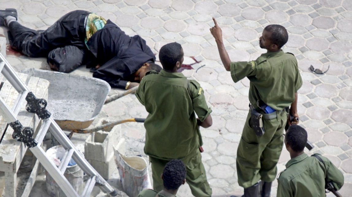 Somali soldiers stand by the body of a hotel worker, left, who died following two explosions which occurred near the gate of the temporary home of Somalia's new president Hassan Sheikh Mohamud, in Mogadishu, Somalia, Wednesday, Sept. 12, 2012. (AP Photo/Farah Abdi Warsameh)