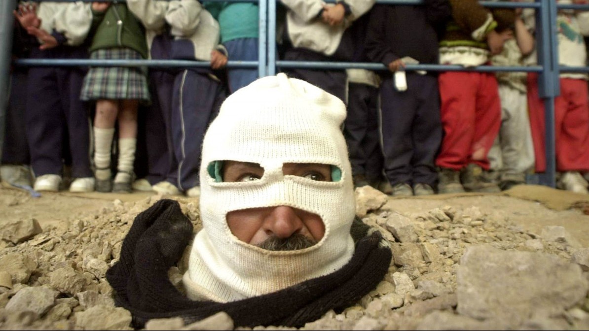 Buried up to his head, a community leader stages a protest at a Catholic Church in poor neighborhood of southern Bogota, Colombia Wednesday, June 12, 2002. (AP Photo/Javier Galeano)
