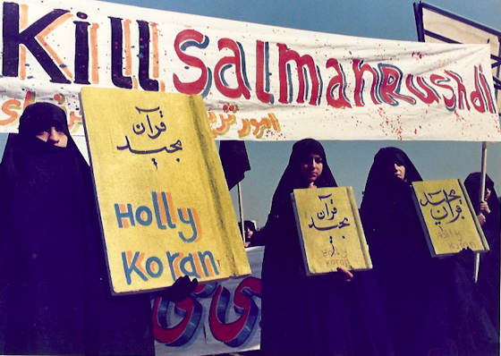 Iranian women protesters hold a sign that reads, "Holy Koran" below a banner which reads, "Kill Salman Rushdie" during a march in Tehran condemning the author in February 1979. (Photo by Norbert Schiller/MintPress)