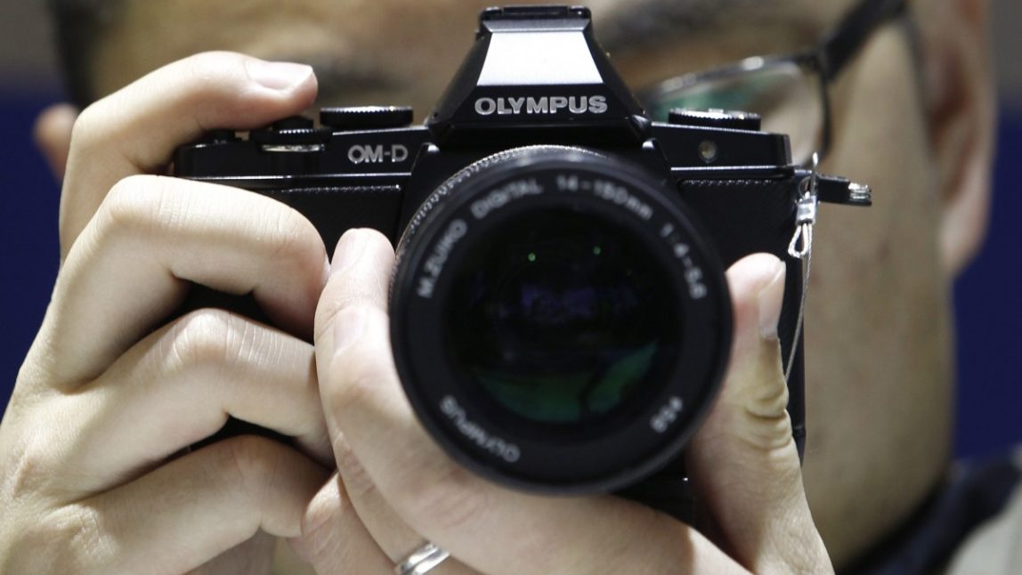 A Chinese visitor tries an Olympus digital camera during the China Photograph and Electrical Imaging Fair in Beijing, Friday, April. 20, 2012. (AP Photo/Vincent Thian)