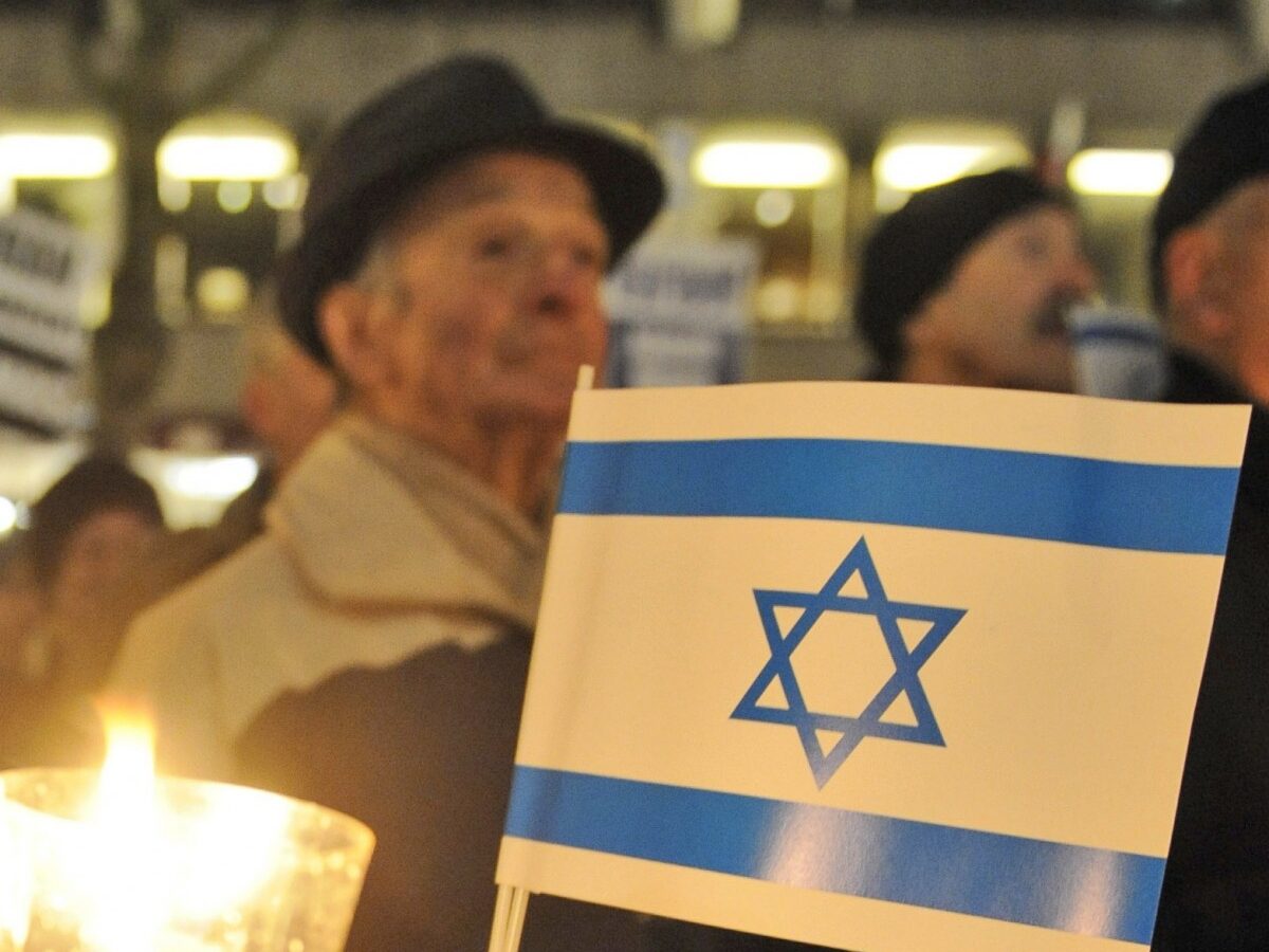 A woman holds a candle and an Israeli flag during a pro-Israel demonstration. (AP Photo/Fabian Bimmer)