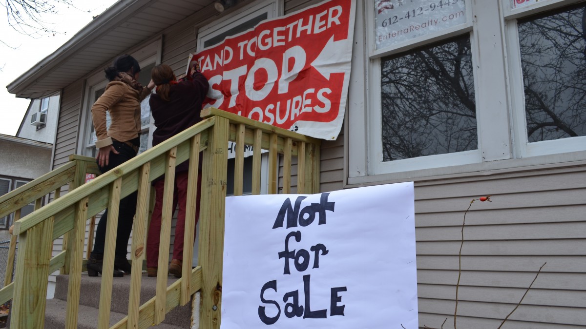 Activists with Occupy Homes Minnesota tape signs to a Minneapolis home Thursday night, declaring that it is not for sale. Occupy Minnesota activists have been working with the Cruz Family, who owns the home and has been attempting to work with Freddie Mac to buy it back. (Photo Trisha Marczak/MintPress)
