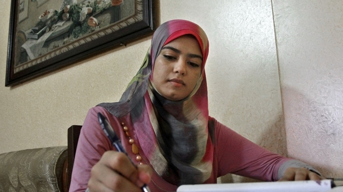 In this Oct. 11, 2012 photo, Palestinian student Amal Ashour, 18, poses for a portrait with schoolbooks at her family house in Gaza City. (AP Photo/Adel Hana)