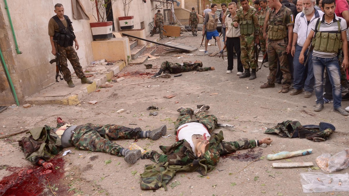 In this photo released by the Syrian official news agency SANA, Syrian security officers, according to SANA gather around three dead suicide bombers, wearing the uniforms of the Syrian army who were killed by security forces before blowing themselves up at the scene where triple bombs exploded at the Saadallah al-Jabri square, in Aleppo city, Syria, Wednesday Oct. 3, 2012. (AP Photo/SANA)