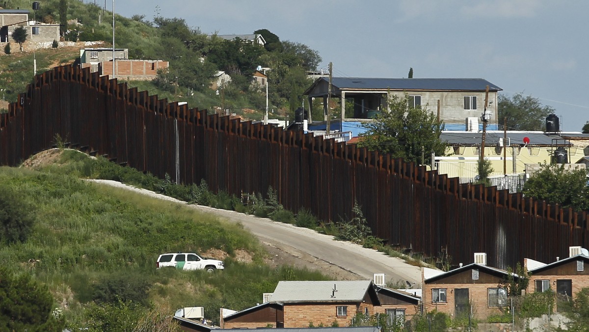 In this photo taken Thursday, Aug. 9, 2012, a U.S. Border Patrol vehicle keeps watch along the border fence in Nogales, Ariz. (AP Photo/Ross D. Franklin)