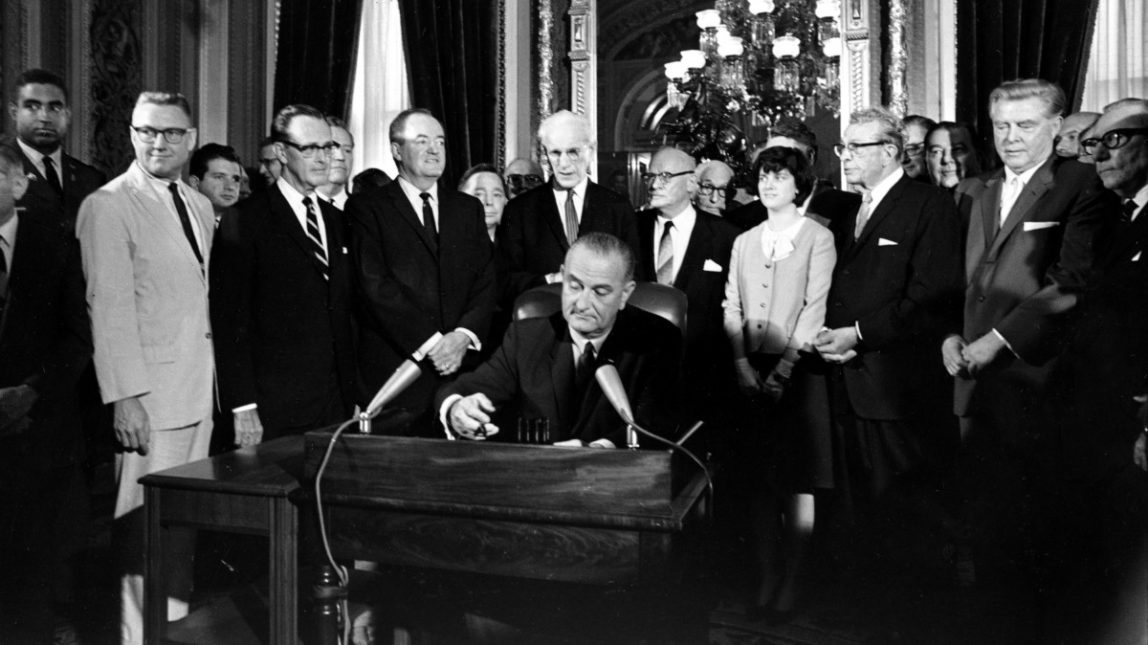 In this Aug. 6, 1965, photo, President Lyndon Baines Johnson signs the Voting Rights Act of 1965 in a ceremony in the President's Room near the Senate Chambers on Capitol Hill in Washington. (AP Photo)