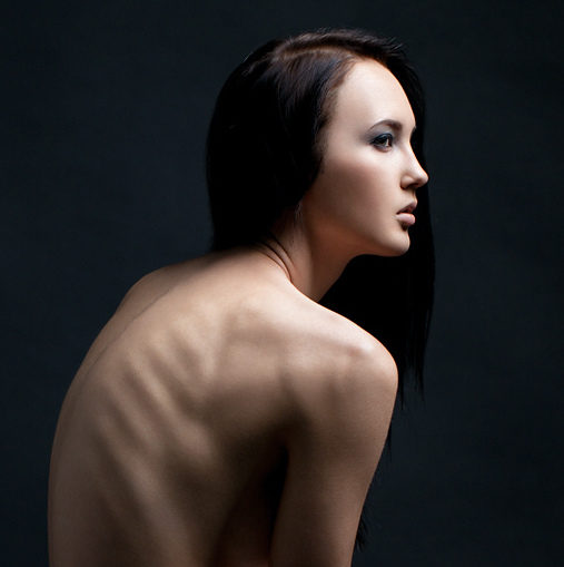 A girl sits during a photo shoot, ribs showing through her skin. (Photo by Danila Panfilov via Flikr)