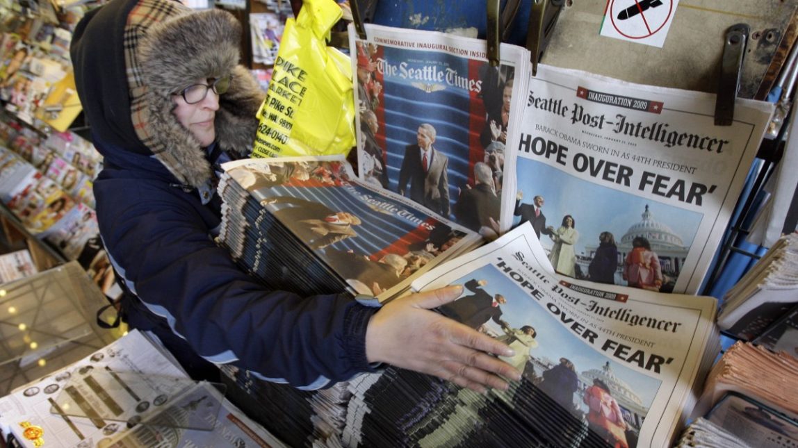 Newspaper vendor Rebecca Steele, adds to the stack of copies of the Seattle Post-Intelligencer at First & Pike News in downtown Seattle Wednesday, Jan. 21, 2009. (AP Photo/Elaine Thompson)