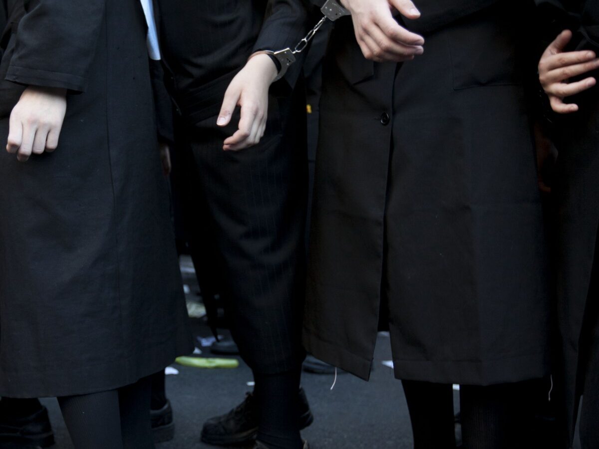 Handcuffed Ultra Orthodox Jewish men and children participate in protest against attempts to draft members of the cloistered community into the Israeli military, in an ultra Orthodox neighborhood in Jerusalem, Israel, Monday, July 16, 2012. (AP Photo/Oded Balilty)