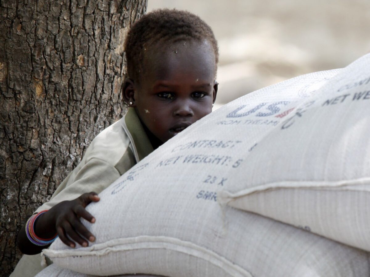 A young Sudanese girl grabs onto one of 60 bags of sorghum for sale donated by USAID and distributed by the World Food Program in Akobo, southern Sudan, Thursday April 8, 2010. (AP Photo/Jerome Delay)