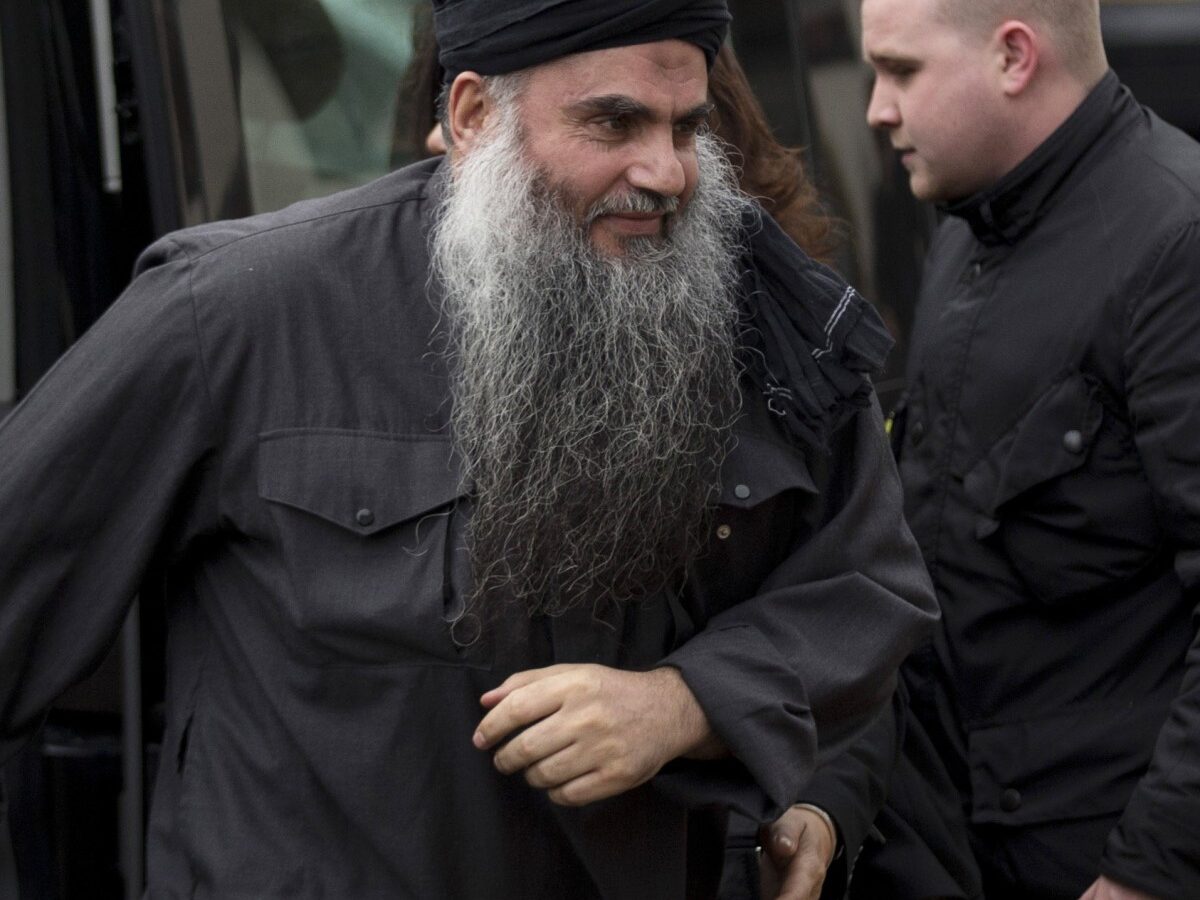 Abu Qatada, left, gets out of the rear of a vehicle as he returns to his residence in London, Tuesday, Nov. 13, 2012. (AP Photo/Matt Dunham)